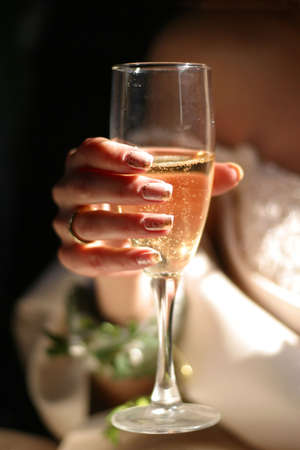 Glass of champagne in a hand of the brideの写真素材