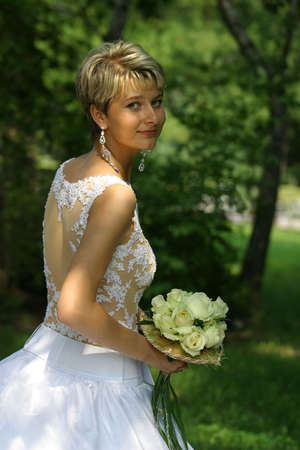 The beautiful bride in park with a wedding bouquet in handsの写真素材