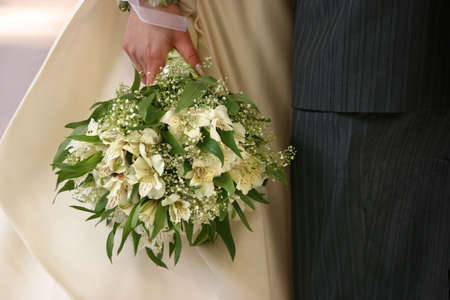 Bouquet of flowers on a background of a dress of the bride and a suit the groomの写真素材