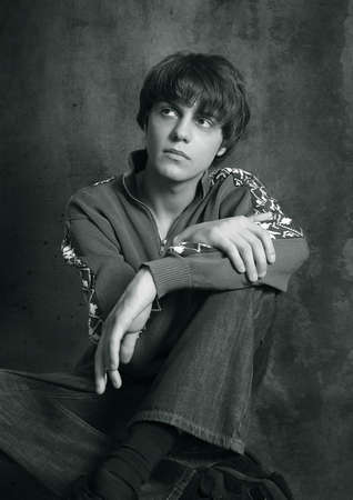 Portrait of the young in studio. Hands are crossed in a lap. b/w+blue toneの写真素材