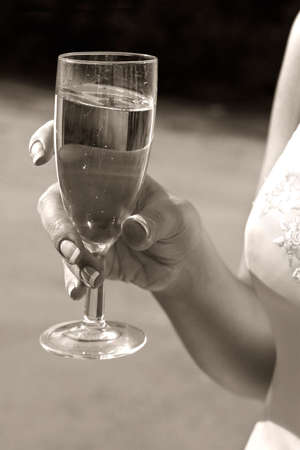 Glass with champagne in hands of the bride. b/w+sepiaの写真素材