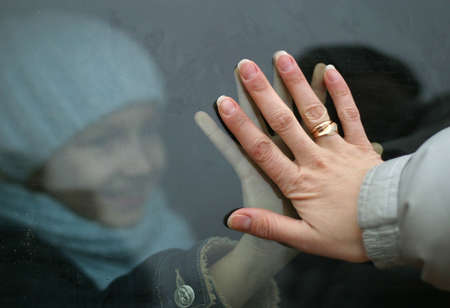 The child concerns a hand through glass of a hand of motherの写真素材