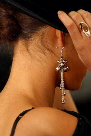 The image of the girl in rings and ear rings putting on a hatの写真素材