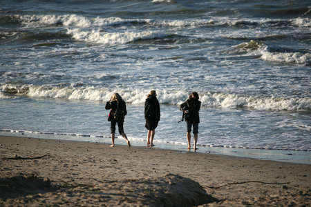 Three girlfriends at coast of the winter seaの写真素材