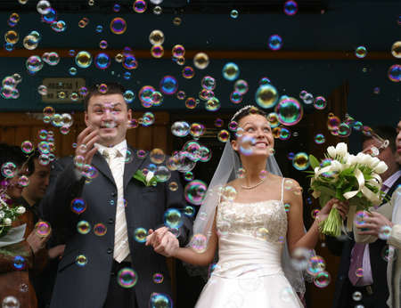 Happy newly-married couple on a background of soap bubblesの写真素材