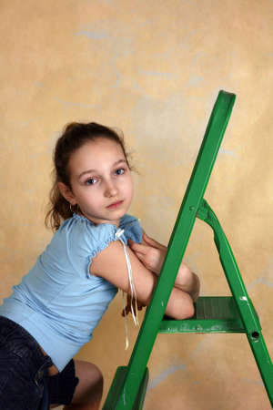 Portrait of the young girl with step-ladder on a yellow backgroundの写真素材