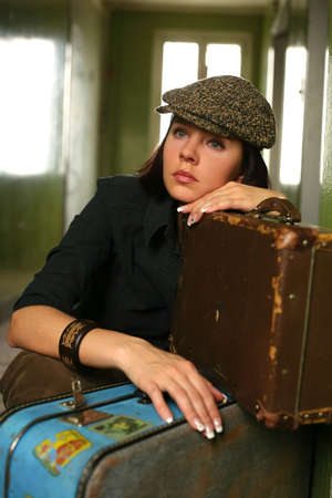 The beautiful woman in a cap sits with two suitcasesの写真素材