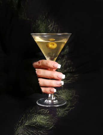 The image of a glass from martinis in a female hand on a black backgroundの写真素材