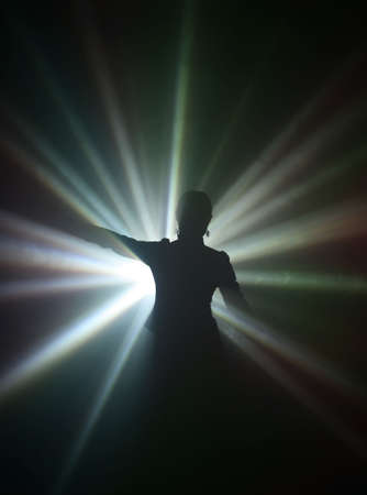 Silhouette of dancing girl in rays of lightの写真素材