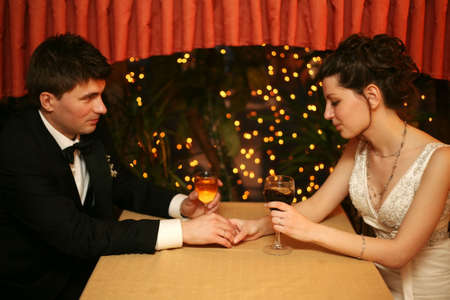 Newly-married couple sharing a glass of wine in restaurant, celebrating or on romantic dateの写真素材
