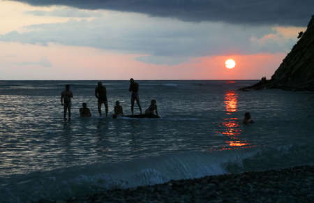 Group of people at coastline on a sunsetの写真素材