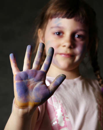 The good little girl. Hands and the face are soiled in a paint