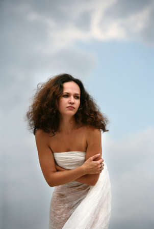 The girl in a white fabric on a background of the skyの写真素材