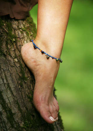 Female leg with a bracelet on a green background