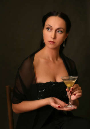 The beautiful woman with a glass of martini on a dark backgroundの写真素材