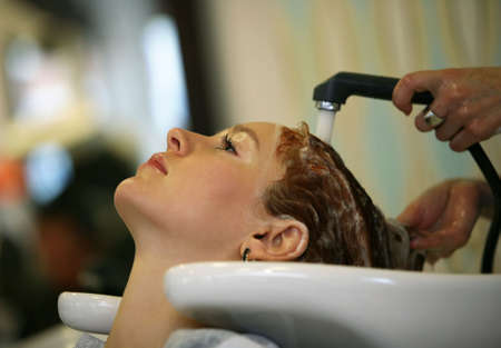 Barber makes a hair-dress to the young brunette