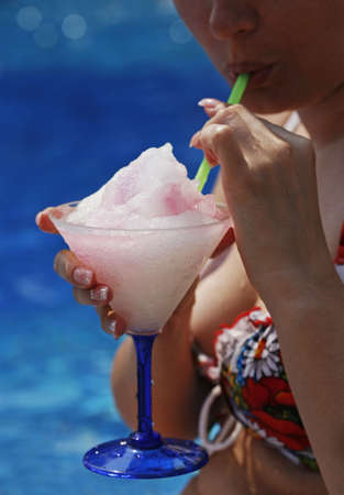 The woman drinks a cocktail on a background of the seaの写真素材