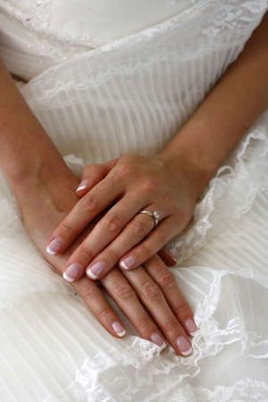 Hands of the bride on a background of a wedding dressの写真素材