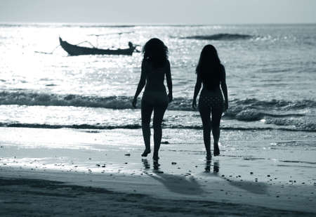 Two silhouettes of girls at coast of oceanの写真素材