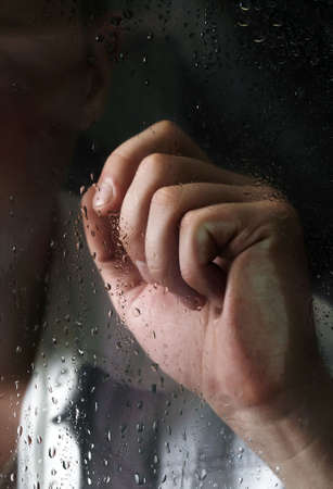 Man's hand behind wet glassの写真素材