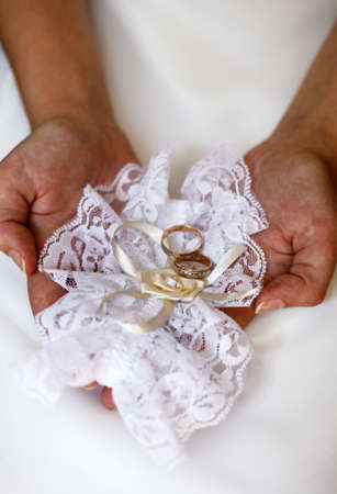 Hands of the bride with a garter and wedding rings