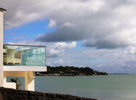 Glass balcony with furniture on a background of coast of Pacific ocean. New Zealandの写真素材