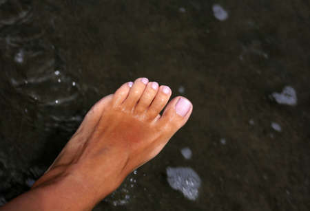 Sunburnt female leg on damp sandの写真素材