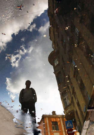 Reflection of a building, clouds and men in waterの写真素材