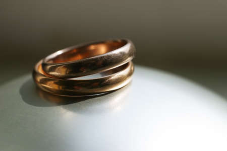 Two gold wedding rings on a grey backgroundの写真素材