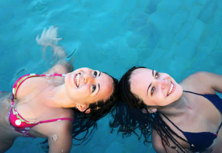 Two beautiful woman enjoying summer in the poolの写真素材