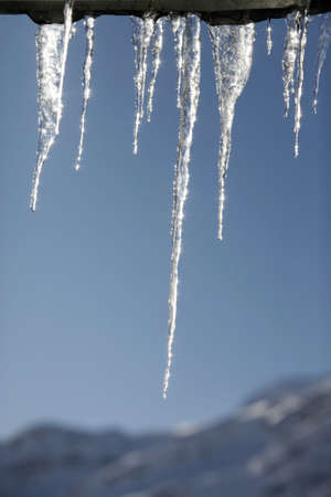 Icicles on a background of the blue sky and mountains