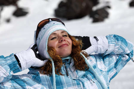The happy girl in a blue ski suit on a background of snowの写真素材
