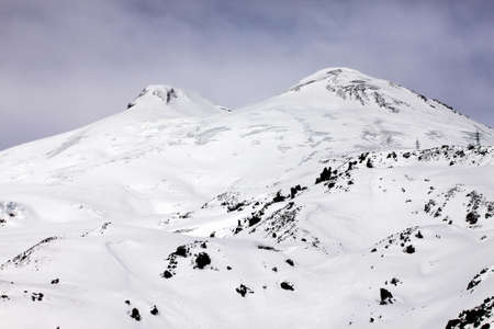 Elbrus is a two-peak cone of a volcano. The western top has height of 5642 m, East - 5621 m. They are divided by a saddle - 5200 m and will defend from each other approximately on 3 kmの写真素材