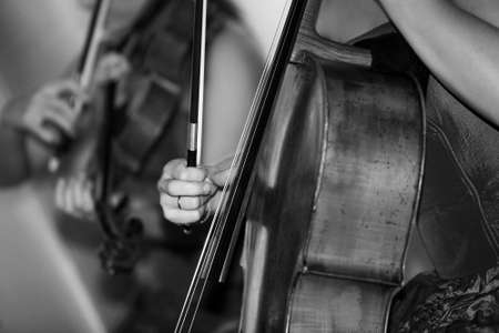 Hands of the musician playing on ï¿½violoncello on a dim backgroundの写真素材