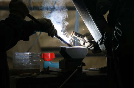 Workers welding metal and sparks spreading