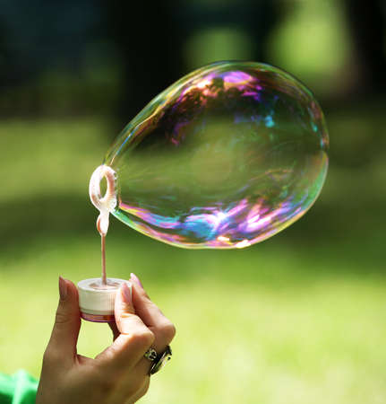 The girl makes big soap bubble in parkの写真素材