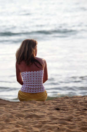 The girl on coastline ocean admires a sunsetの写真素材