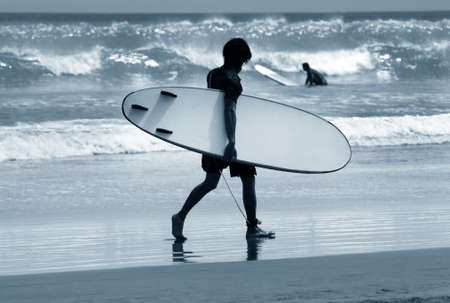 Man-surfer with board on a coastline. Bali. Indonesia
