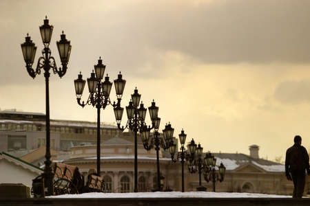 The lonely passer - by in evening square with lanterns. Moscow, Russiaの写真素材