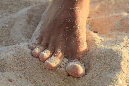 Men's leg is on the sandy white beach
