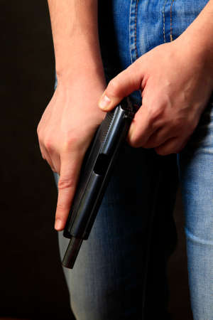 Black pistol in a man's hand on dark background