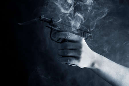 Black pistol in a man's hand on a smoke
