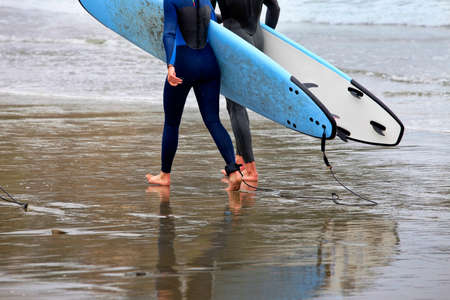Surfers holding a surfboard at the beach