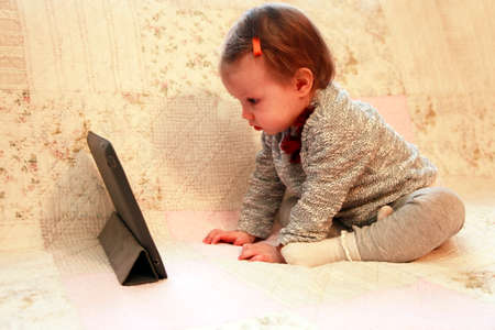 Small girl staring tablet at homeの写真素材