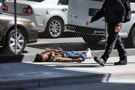 Los Angeles, CA, USA - September 23, 2011: Homeless man sleeps on the street near the fence in the center of Los Angelesのeditorial素材