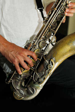 Hands of the saxophonist with a saxophone