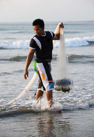Kuta, Bali, Indonesia - October 22, 2007: Unknow adult man with a network, fishing in a sunset 22 October 2007 on Bali, Indonesia.のeditorial素材