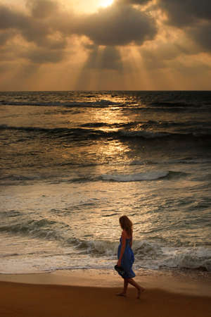 The lonely girl on a beach on sunsetの写真素材