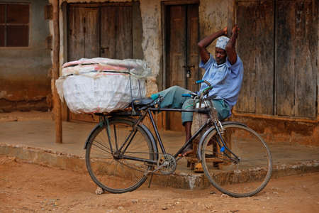 Stone Town Zanzibar, Tanzania - January 10, 2016: A adult man with a bike on background old wall in Stone Town, Zanzibar.のeditorial素材