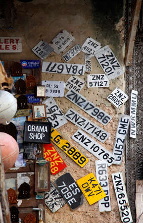 Stone town, Tanzania - December 30, 2015: Stone Town. Streets of the town are always lively. There are many shops, restaurants and bars, where tourists can relax and buy suvenirs. Here is a man apparently collecting old number plates.のeditorial素材